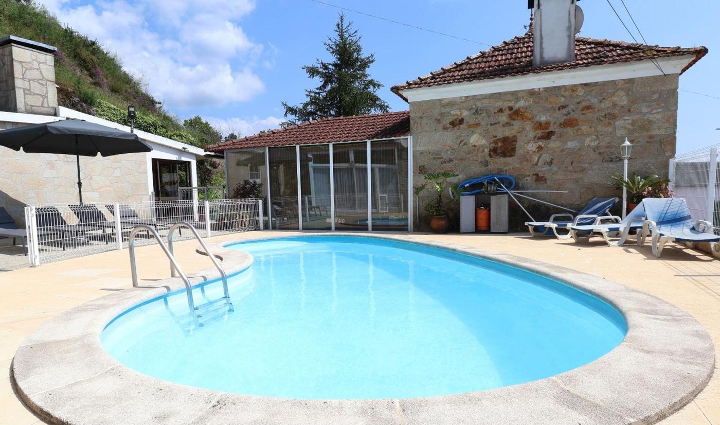 Piscina exterior com espreguiçadeiras e chapéu de sol